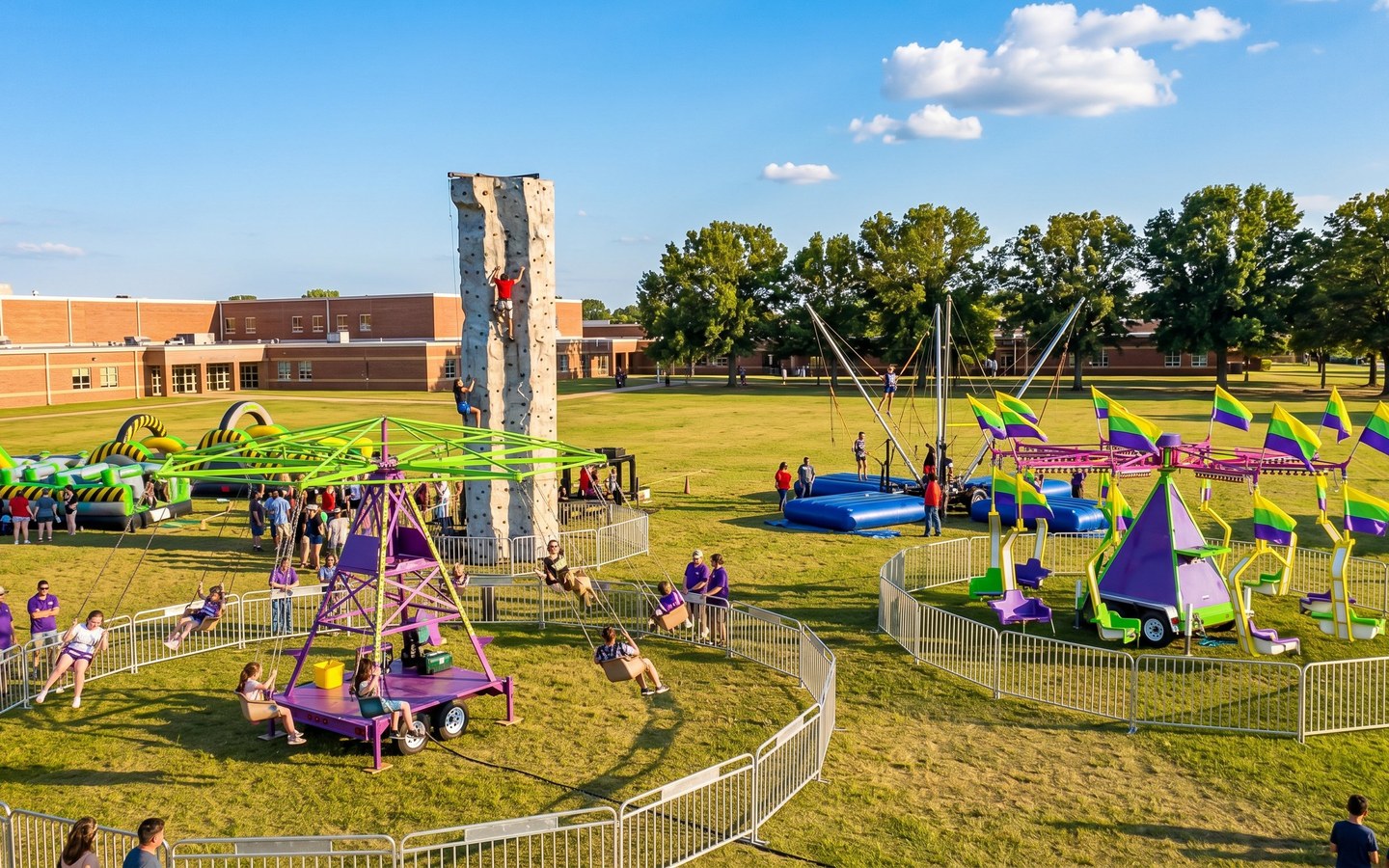 Austin TX carnival rides at school event - swing rides, rock climbing wall, bungee trampolines and obstacle courses